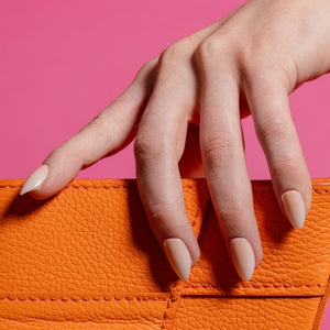 Hand met Blush Rush ombre almond press on nails en oranje clutch - Freaky Nails