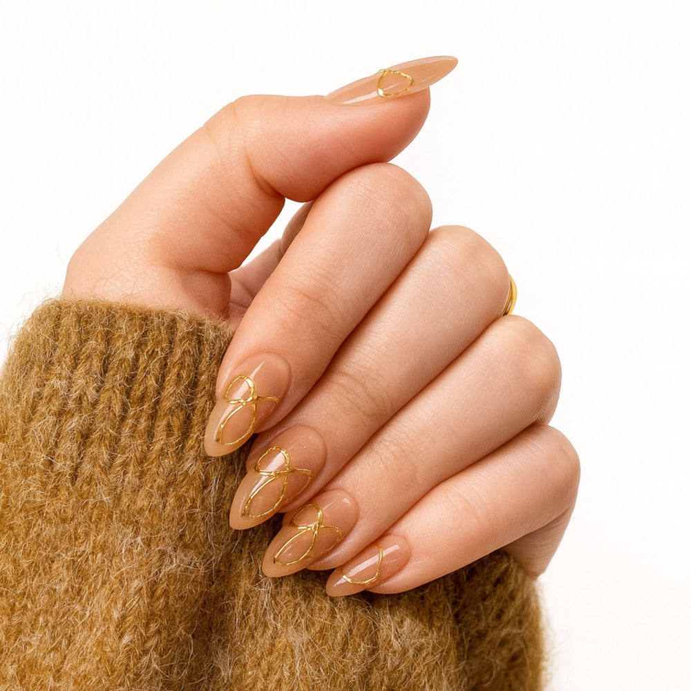Nude press-on nagels met gouden strikjes in almond vorm, Golden Bow Babe van Freaky Nails.