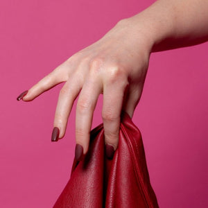 Hand met Velvet Rebel bordeauxrode square press on nagels en rood accessoire - Freaky Nails