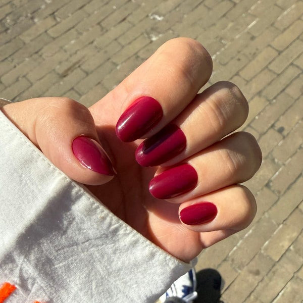 Hand met Berry Me rode short oval press on nagels in natuurlijk licht - Freaky Nails