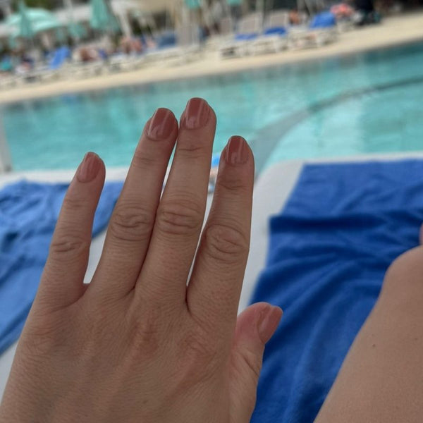 Hand met Spice Up Nude nude short square press on nagels bij het zwembad - Freaky Nails